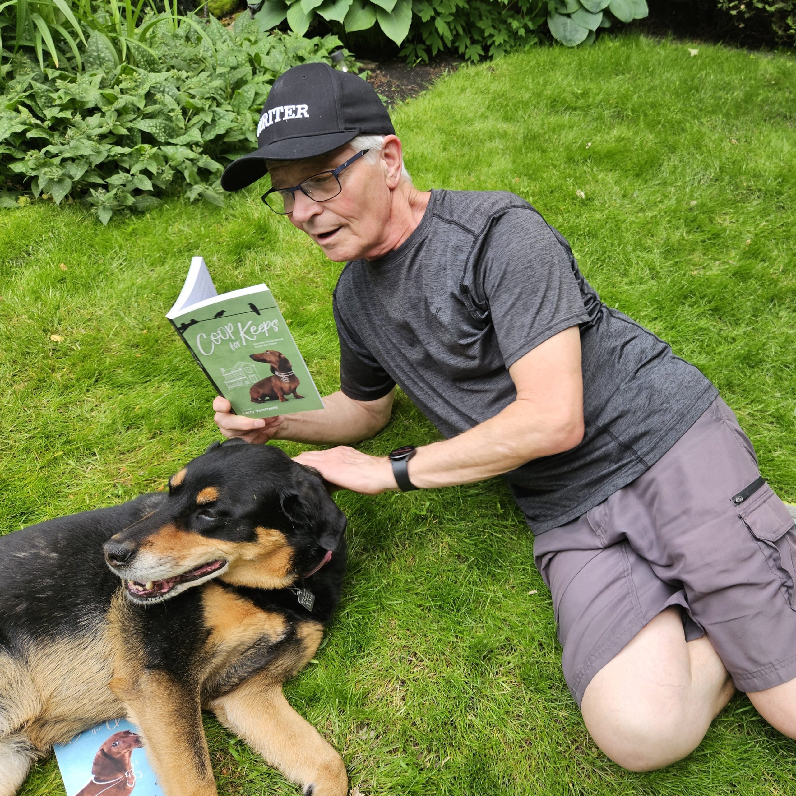 Larry lays beside his dog in the grass and reads from Coop For Keeps. Coop recently won the MYRCA award for 2026.